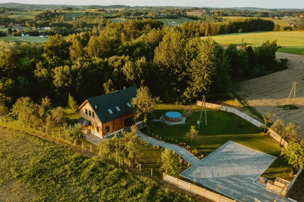 Dom z drona latem: ogród, żwirowa ścieżka, las i pola dookoła